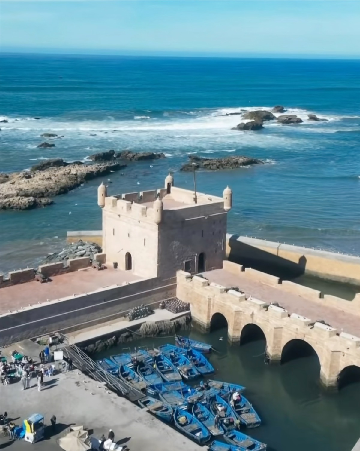 The stone arches of the Skala du Port and blue fishing boats